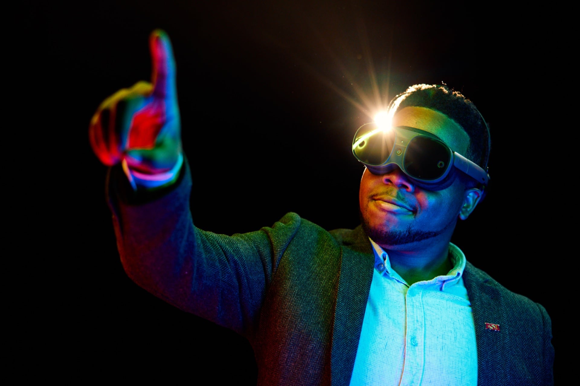 A person wearing futuristic AR goggles reaches forward in colorful light, suggesting exploration of artificial intelligence and immersive technology.