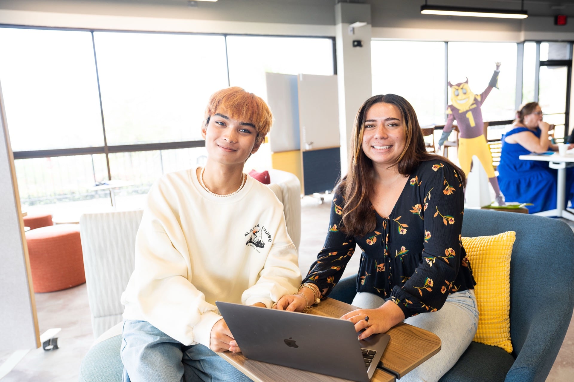 Two students work together on a laptop in a bright campus lounge, representing the welcoming learning environment at ASU Local–West Hawai‘i.