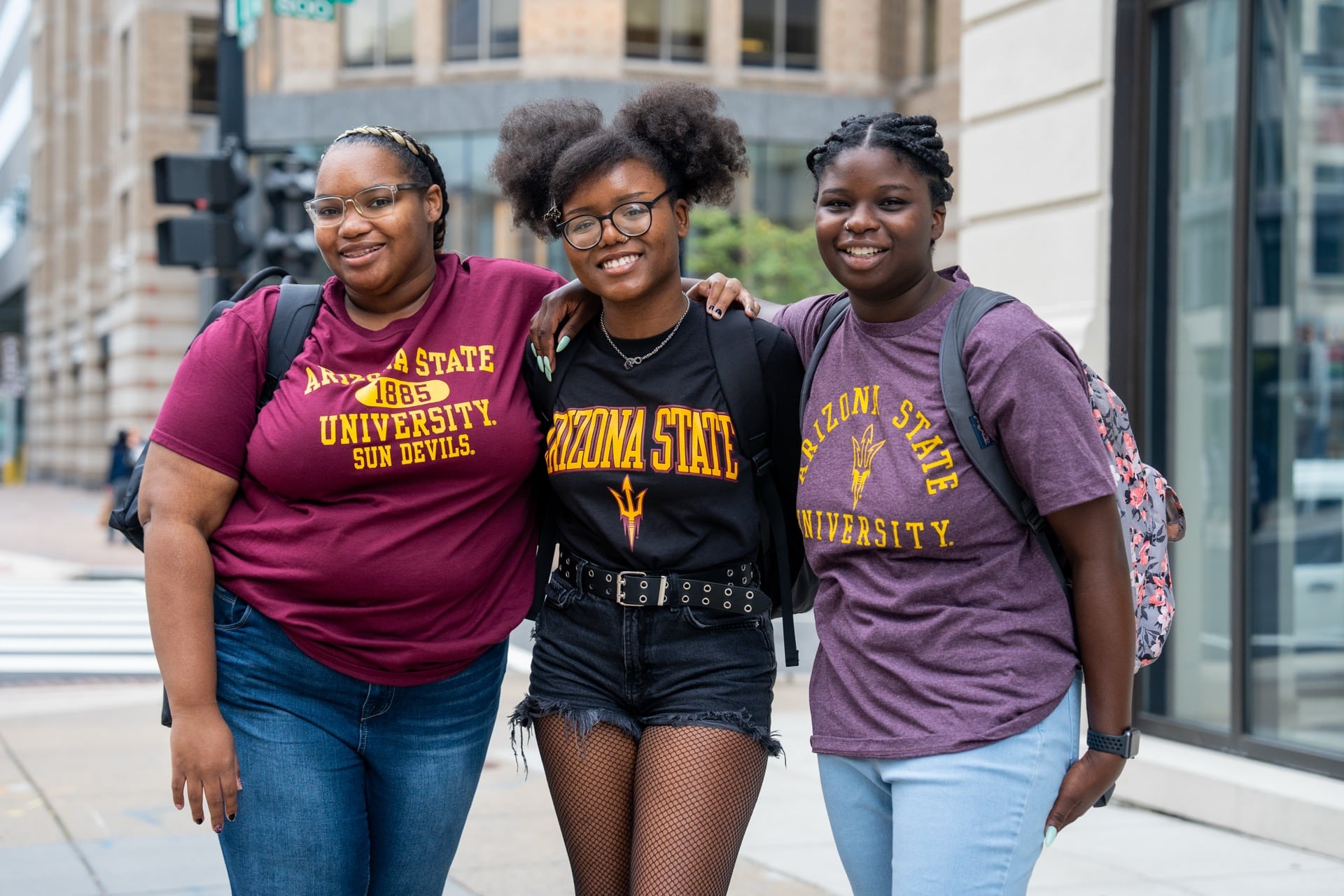 Three students wearing ASU gear stand together smiling on a city sidewalk, representing the ASU Local community in Washington, DC.