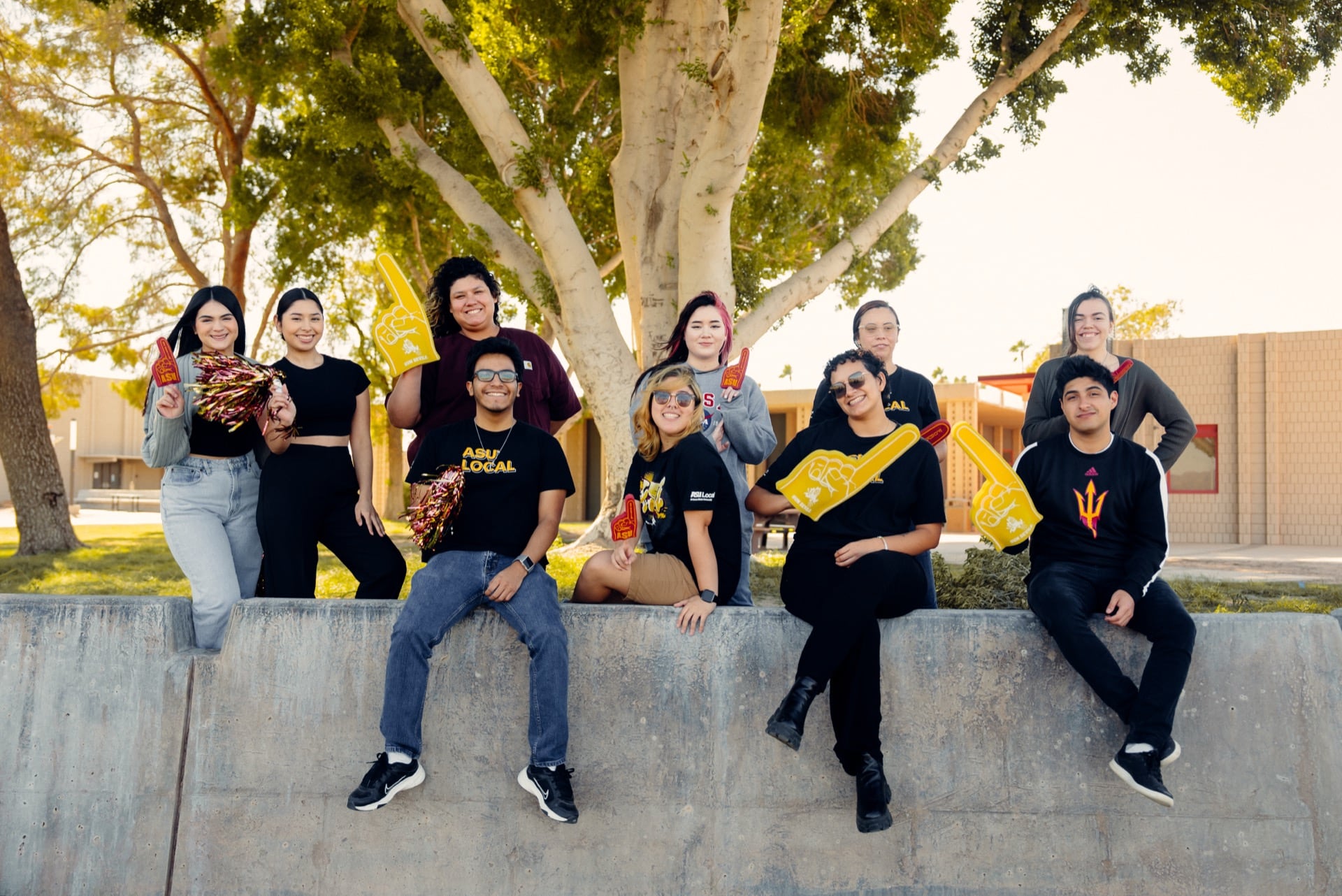 A group of students sit and stand together outdoors with ASU spirit gear, representing the vibrant student community in Yuma.