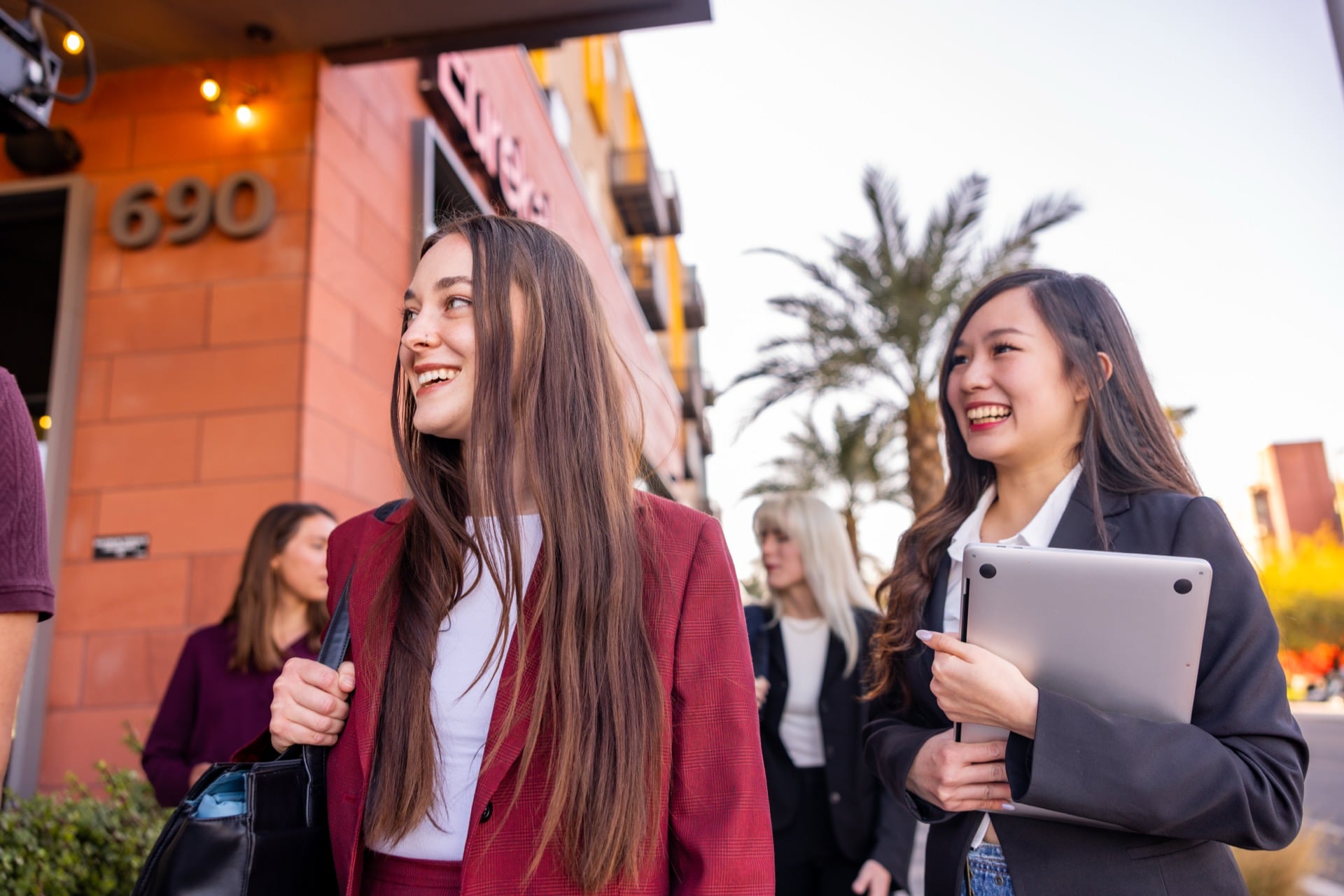 Young professionals walking together in business attire and smiling outdoors, reflecting collaboration and developing professional skills.
